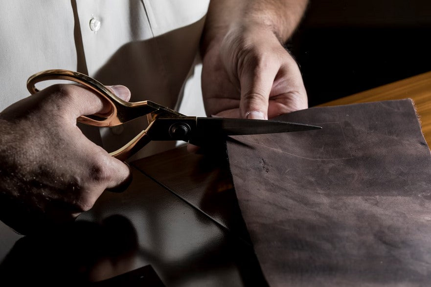Close-up of premium leather being precisely cut during wallet manufacturing, showcasing craftsmanship and full grain leather processing.